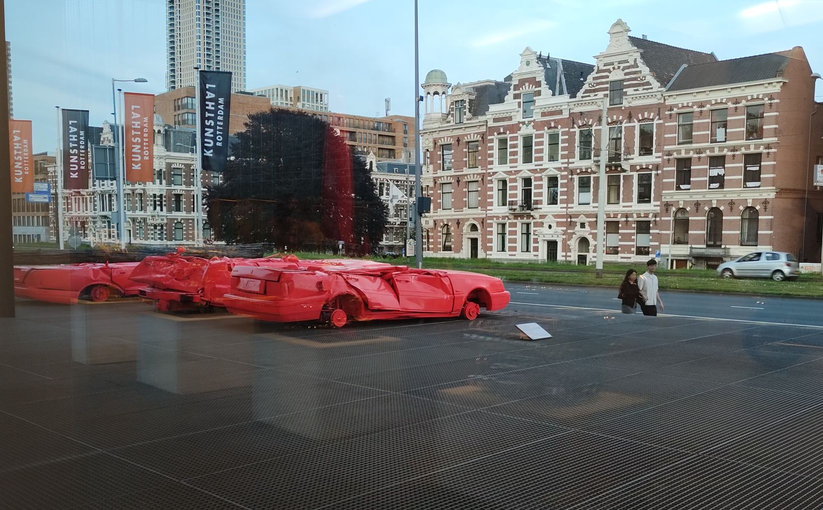6(9): Demolierte Karossen ehemaliger Luxusautos auf dem Vorplaz der Kunsthal ziehen die Blicke der Rotterdamer Passanten an.